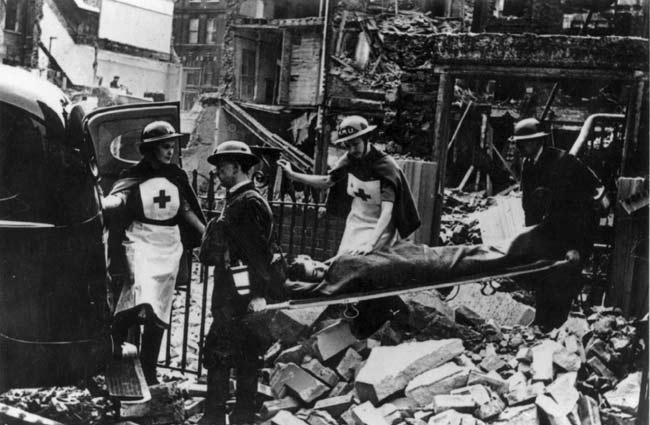 Second World War volunteers carry an injured person away from a bombed building