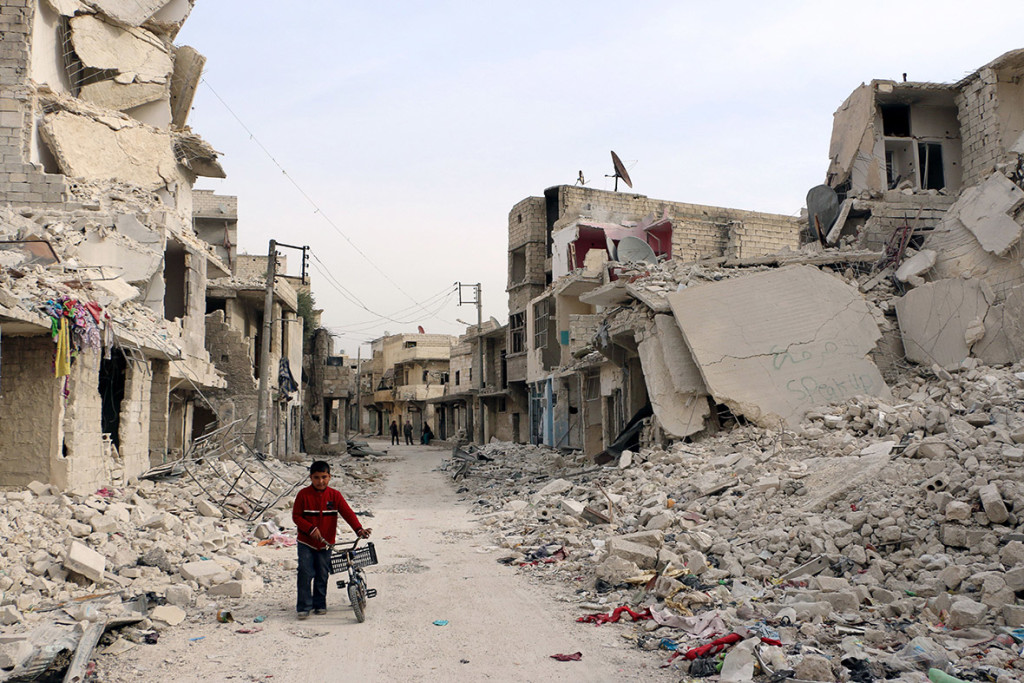 A Syrian boy walks with his bicycle in the devastated Sukari district of Aleppo on 13 November, 2014 (AFP)
