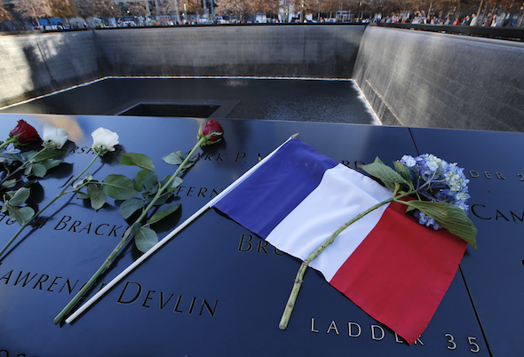 A French flag and flowers sit on the engraved names at the 9/11 Memorial South Pool, at the National September 11 Memorial and Museum Monday, Nov. 16, 2015, after a ceremony remembering victims of the Paris terrorist attacks and in a show of unity with French citizens in New York. (AP Photo/Kathy Willens)