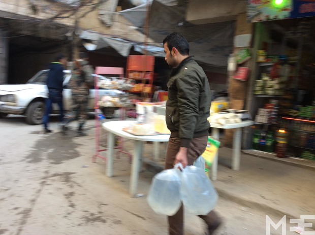 A man carries water in government-held Aleppo (MEE / Peter Oborne)