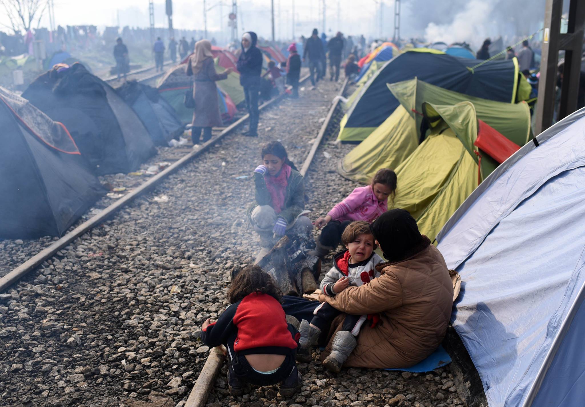 Refugees from Mideast wars camped along rail lines in Greece.