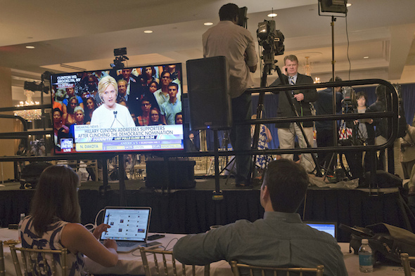 Democratic presidential candidate Hillary Clinton is seen on a television monitor addressing her supporters, as reporters file their stories after a June 7 news conference by presumptive Republican nominee Donald Trump. (Mary Altaffer / AP)