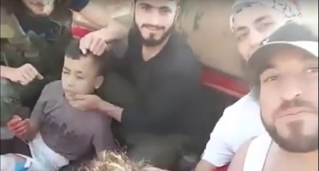 U.S.-backed Syrian “moderate” rebels smile as they prepare to behead a 12-year-old boy (left), whose severed head is held aloft triumphantly in a later part of the video. [Screenshot from the YouTube video]