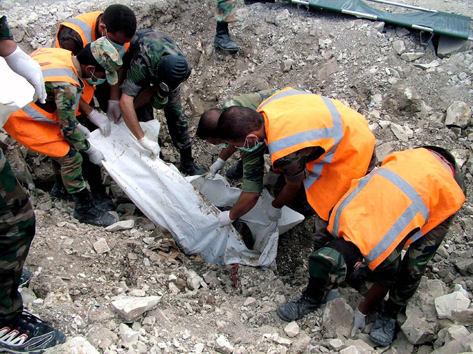 A handout picture released by the Syrian Arab News Agency (SANA) on August 20, 2013 shows soldiers loyal to the regime forces wrapping a decomposed body that was allegedly discovered in a mass grave in northern Latakia, a province on the Mediterranean coast (AFP Photo)