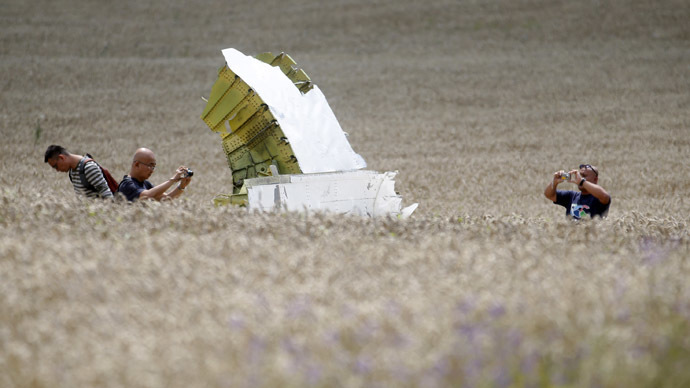 Malaysian air crash investigators take photos of the crash site of Malaysia Airlines Flight MH17, near the village of Hrabove (Grabovo), Donetsk region July 22, 2014. (Reuters/Maxim Zmeyev)